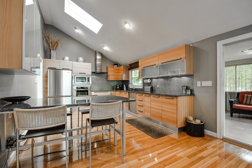 20 Rutledge Road Natick, MA 01760 - Photo 6 of 29 a kitchen with granite countertop a table chairs microwave and cabinets