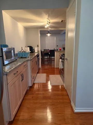 a kitchen with stainless steel appliances granite countertop a refrigerator a sink dishwasher and a wooden cabinets