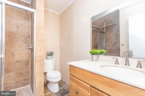 a bathroom with a granite countertop sink a toilet and shower
