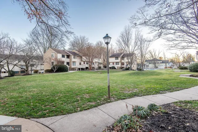a white house with a big yard plants and trees