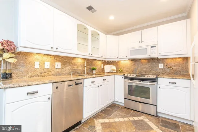 a kitchen with granite countertop white cabinets and white appliances