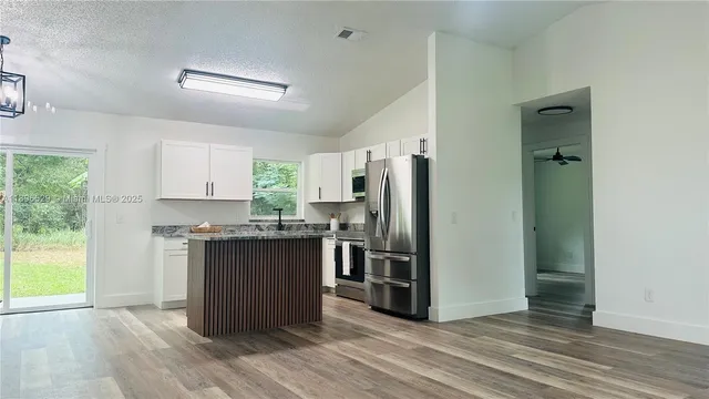 a kitchen with stainless steel appliances granite countertop a refrigerator and a stove top oven