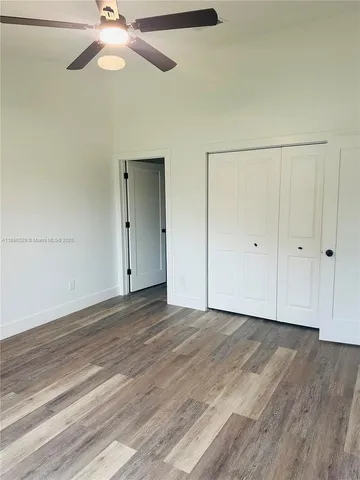 an empty room with a ceiling fan and wooden floor