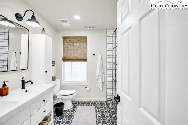 a spacious bathroom with a double vanity sink toilet mirror and shower
