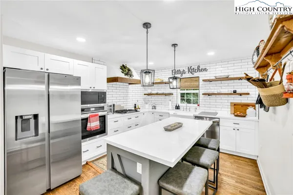 a kitchen with stainless steel appliances a refrigerator a stove a sink and white cabinets