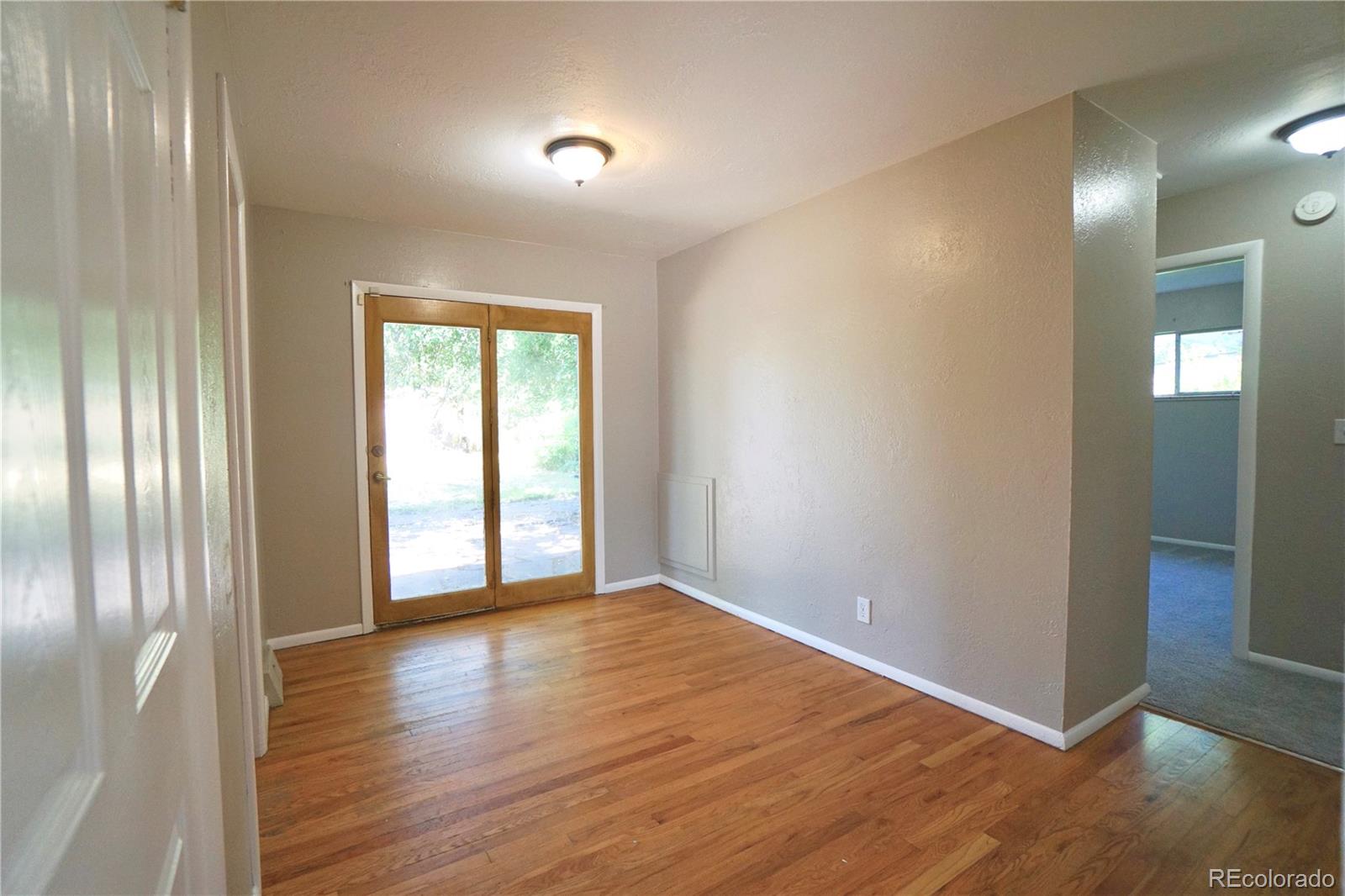 2519 15th Avenue Greeley, CO 80631 - Photo 7 of 25 an empty room with wooden floor and windows with curtains