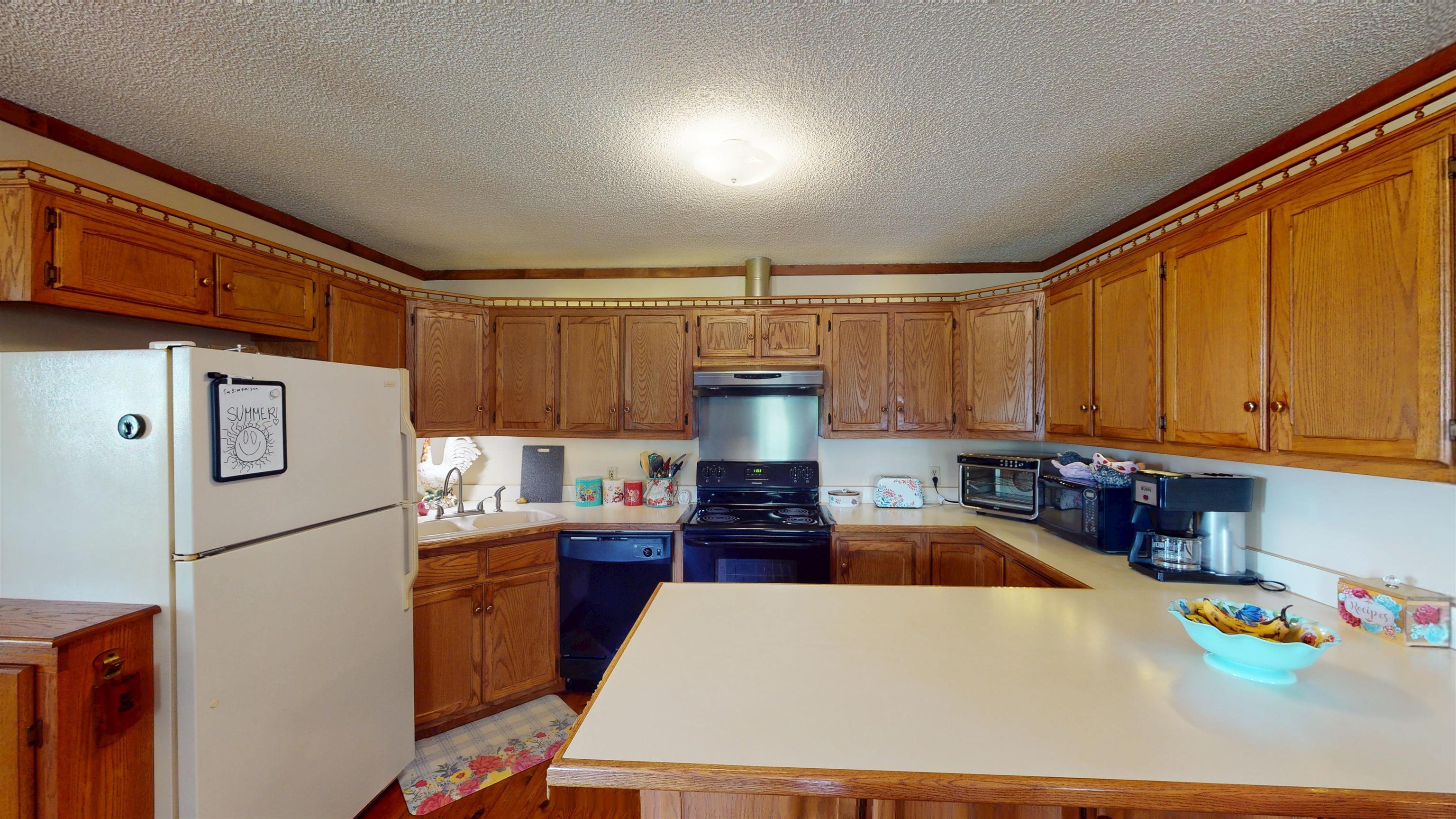 420 Joann Road Somerville, TN 38068 - Photo 7 of 40 U-shaped kitchen layout featuring wood cabinetry, light-toned countertops, and a built-in range with an overhead microwave