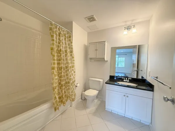 a bathroom with a granite countertop sink a toilet a mirror and shower