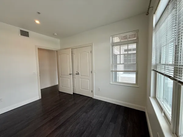 a view of an empty room with wooden floor and a window