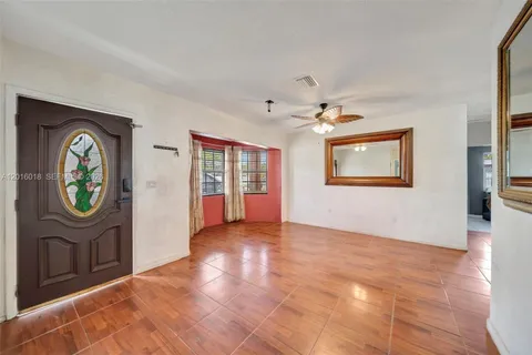 a view of an empty room with window and hardwood floor
