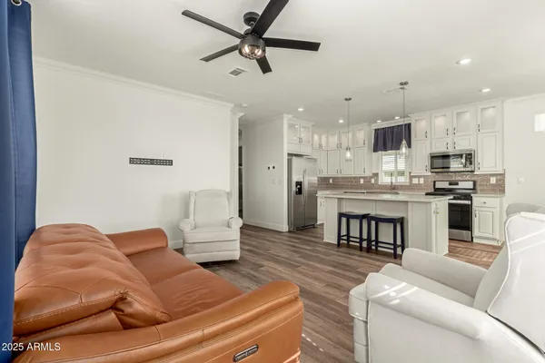 a living room with stainless steel appliances furniture and a kitchen view