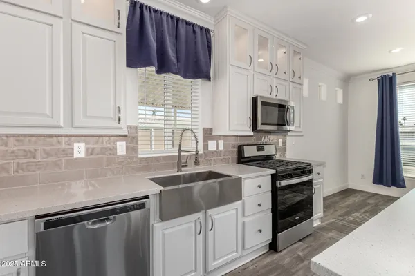 a kitchen with stainless steel appliances granite countertop a sink stove microwave and refrigerator