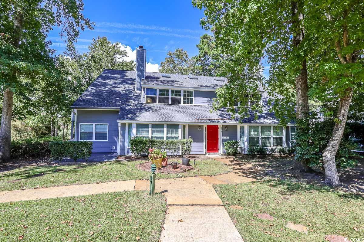 Traditional-style home featuring a front yard, a chimney, and roof with shingles