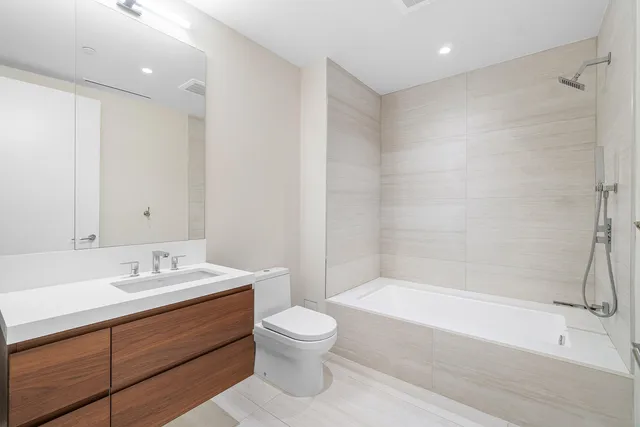 a bathroom with a bathtub shower sink vanity and toilet