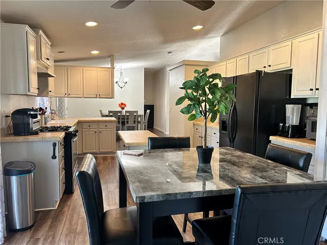 a kitchen with granite countertop a table chairs stove and refrigerator