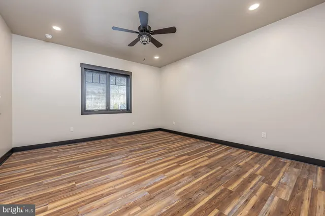 a view of an empty room with a window and wooden floor