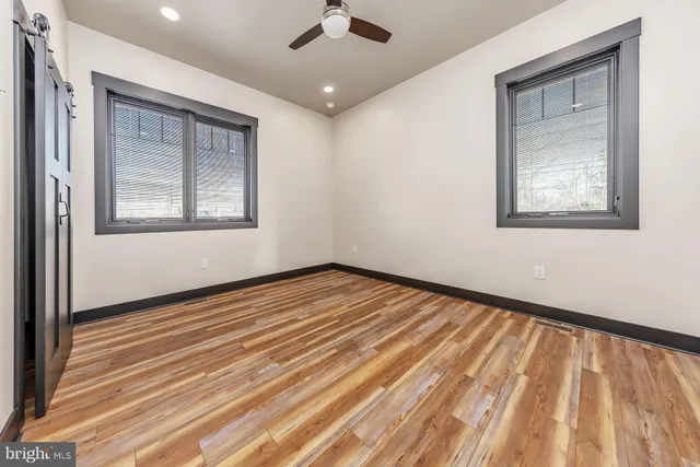 an empty room with wooden floor cabinet and windows