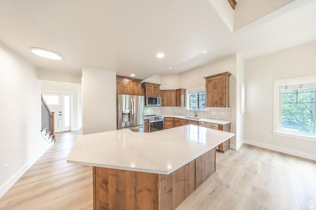 2169 Orchard Pines Loop East Bountiful, UT 84010 - Photo 4 of 32 Spacious kitchen featuring a large island with a white countertop, wood cabinetry, and stainless steel appliances
