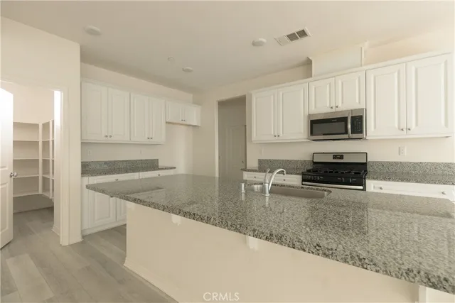 a kitchen with granite countertop a stove a sink and a microwave