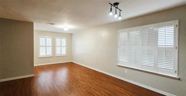 a view of an empty room with wooden floor and a window