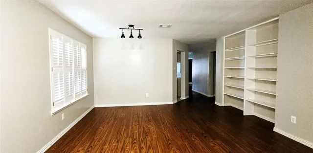 a view of an empty room with a window and wooden floor