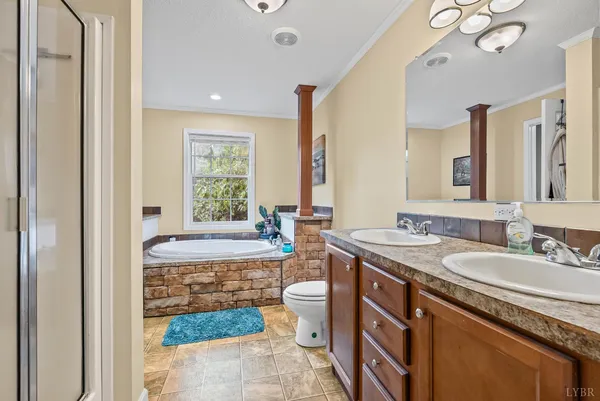 a spacious bathroom with a granite countertop sink a toilet a mirror a bathtub and window
