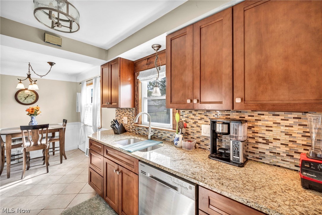 30002 Barjode Road Willowick, OH 44095 - Photo 17 of 33 Kitchen featuring wood finish cabinetry, dishwasher, light stone countertops, light tile patterned floors, and wainscoting