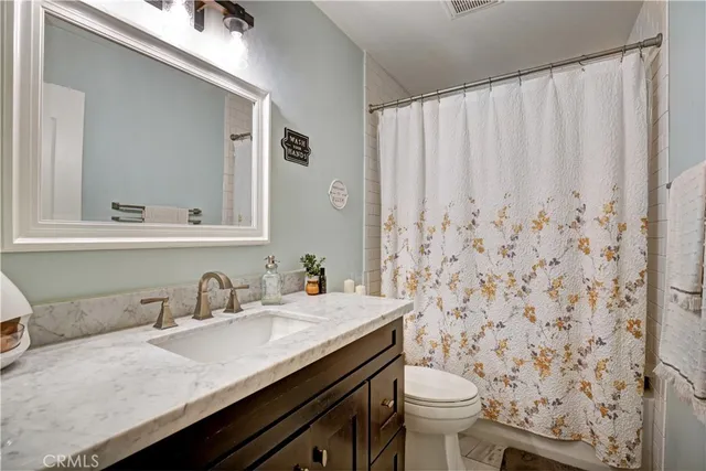a bathroom with a granite countertop sink and a toilet