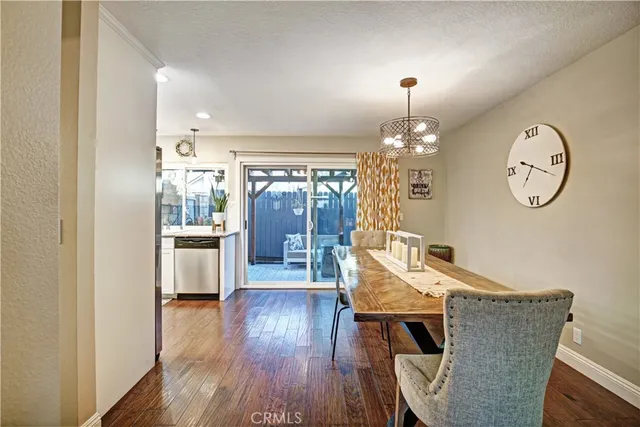 a dining room with wooden floor a chandelier a wooden table and chairs