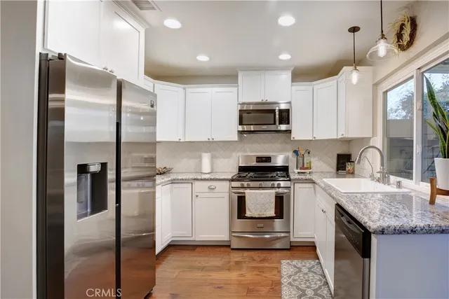 a kitchen with kitchen island granite countertop a stove top oven a sink and a refrigerator