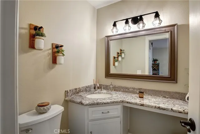 a bathroom with a granite countertop sink and a toilet