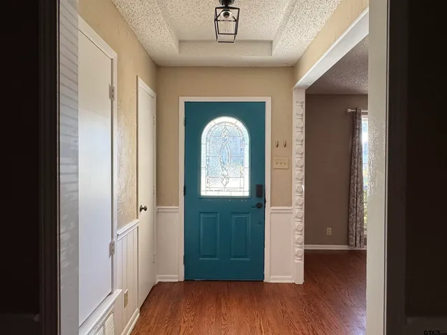 a view of a hallway with wooden floor and front door
