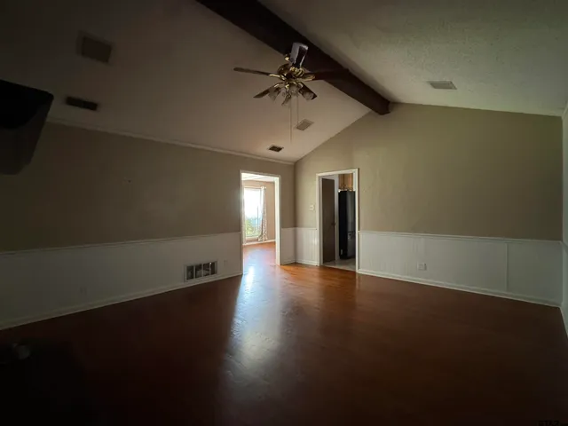 an empty room with wooden floor chandelier and windows