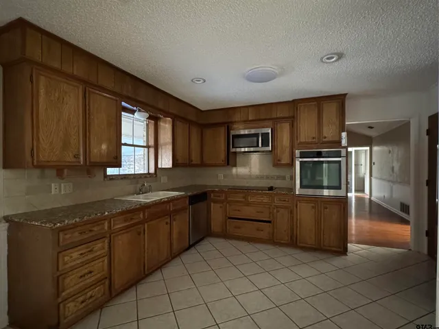 a kitchen with stainless steel appliances granite countertop a sink and dishwasher a stove top oven with wooden floor