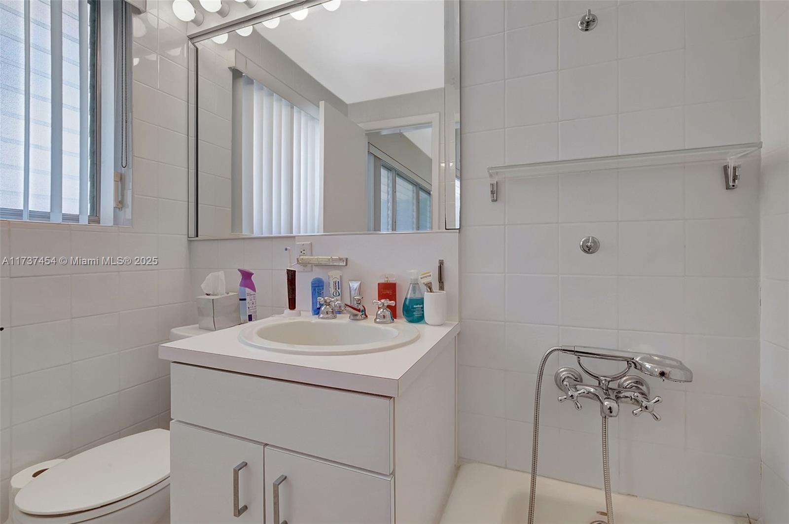 1155 103rd Street, Unit 9B Bay Harbor Islands, FL 33154 - Photo 26 of 43 a bathroom with a sink vanity mirror and toilet