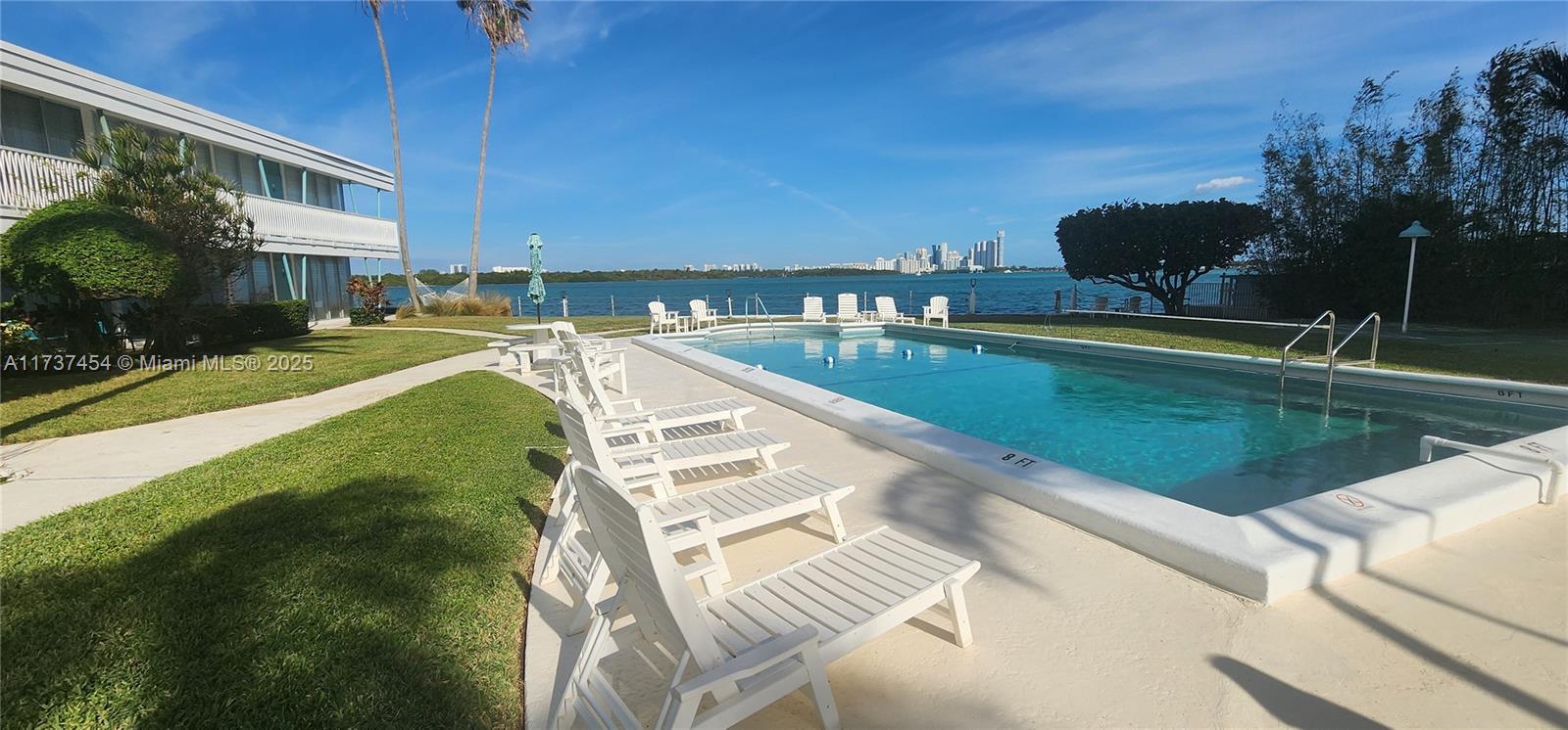 1155 103rd Street, Unit 9B Bay Harbor Islands, FL 33154 - Photo 7 of 43 a view of a swimming pool with a lawn chairs and floor to ceiling window