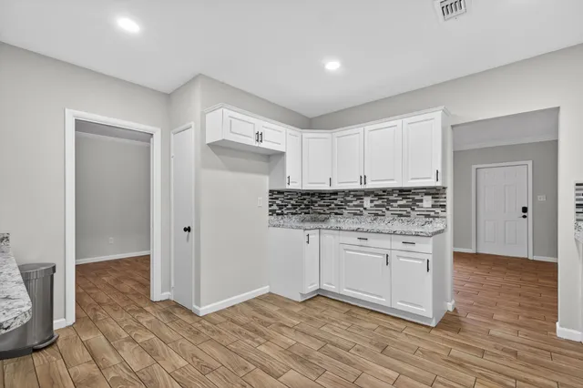 a kitchen with granite countertop white cabinets and stainless steel appliances