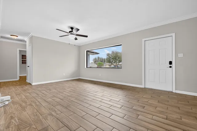 a view of empty room with wooden floor and fan