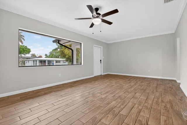 a view of an empty room with wooden floor and a window