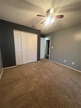 an empty room with windows and fan