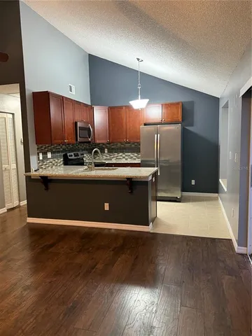 a kitchen with stainless steel appliances wooden floor sink and wooden cabinets