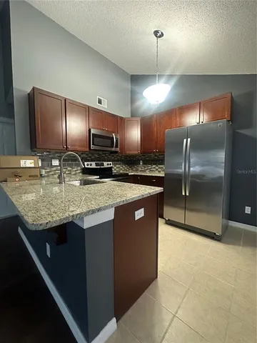 a kitchen with stainless steel appliances granite countertop a sink a stove and a refrigerator