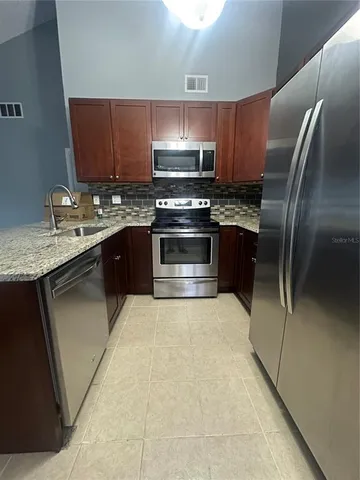 a kitchen with stainless steel appliances granite countertop a stove a sink and a refrigerator