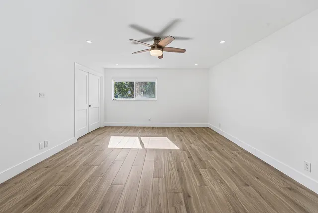 a view of a room with wooden floor and ceiling fan