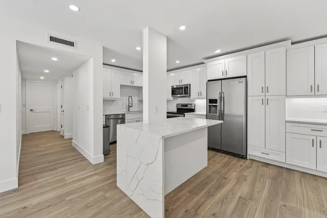 a open kitchen with kitchen island white cabinets and wooden floor