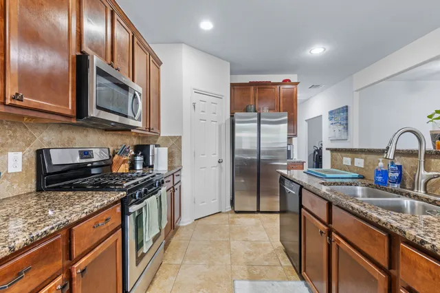 a kitchen with stainless steel appliances granite countertop a sink stove refrigerator and cabinets