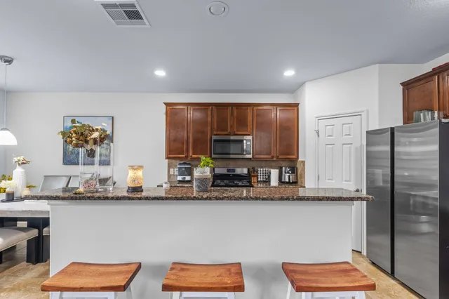 a kitchen with stainless steel appliances granite countertop a refrigerator and a stove top oven
