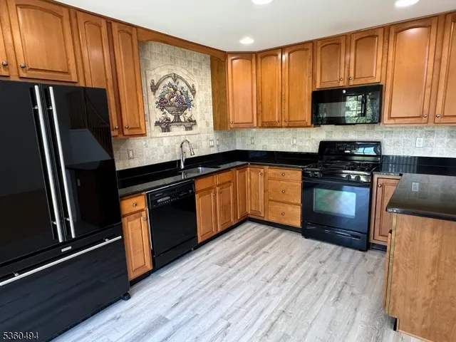a kitchen with granite countertop wooden floors stainless steel appliances and a sink