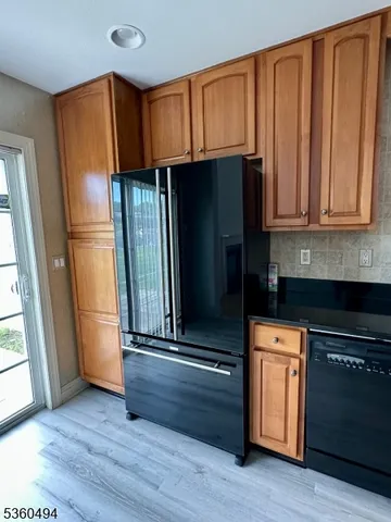 a kitchen with granite countertop wooden cabinets and a refrigerator