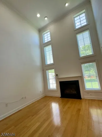 an empty room with windows fireplace and wooden floor
